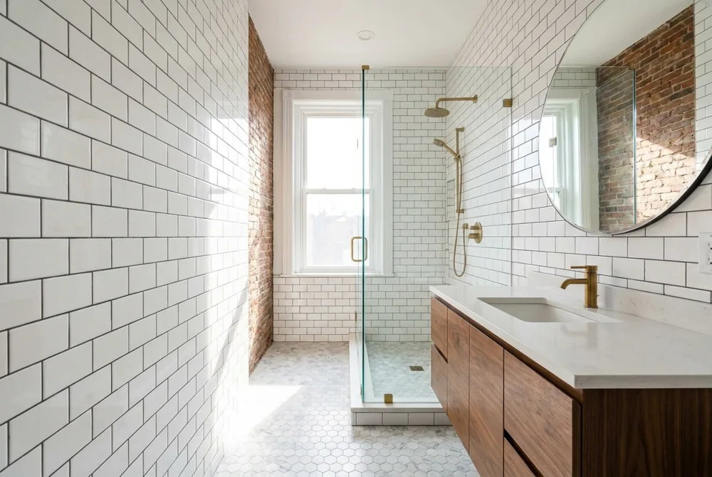 A renovated Baltimore rowhome bathroom with white subway tile, a frameless glass walk-in shower, and a floating wood vanity